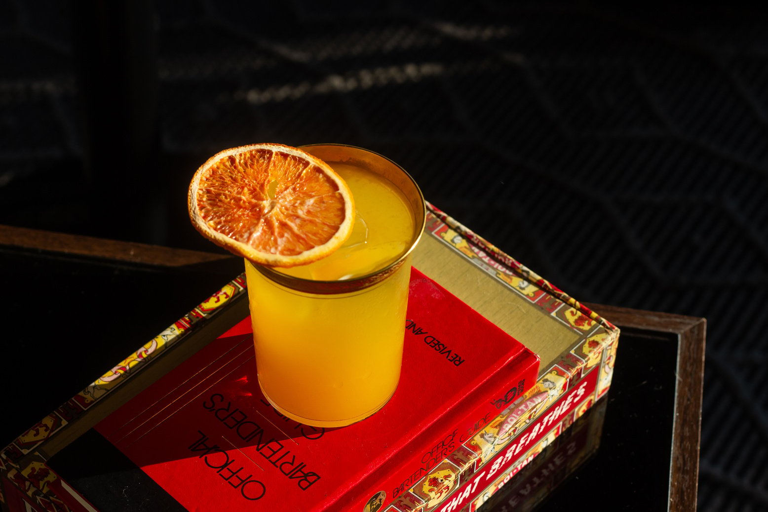 cocktail glass with vibrant orange drink garnished with a dehydrated orange slice